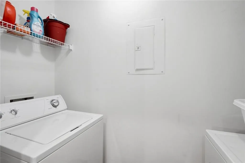 Dedicated laundry area with a white wire shelf for storage and a visible electrical panel
