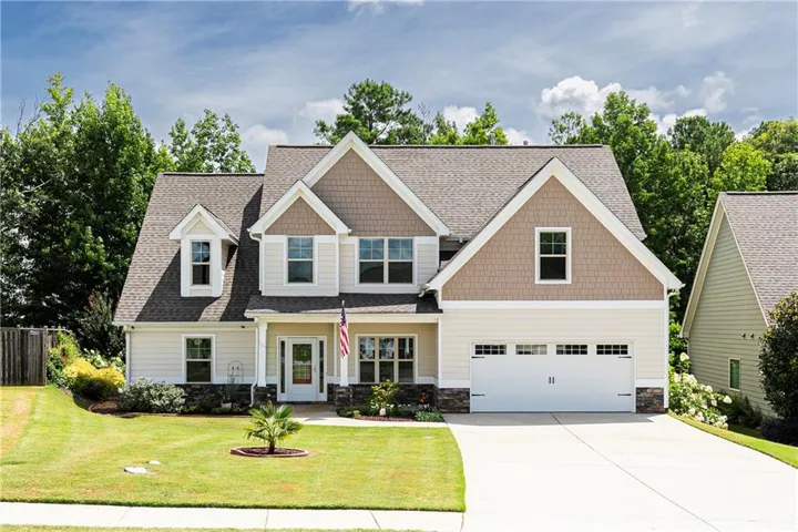 Gable-roof property featuring a two-car garage, stone accent siding, and dormer windows