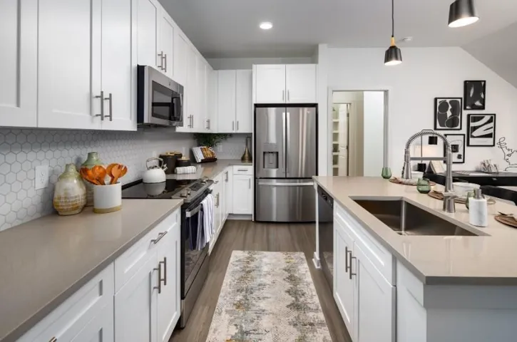 Kitchen featuring stainless steel appliances, white cabinets, and light stone counters