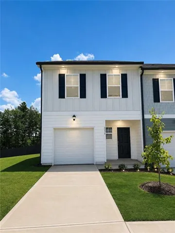 Modern two-story residence featuring a clean white exterior with black-trimmed windows and vertical siding