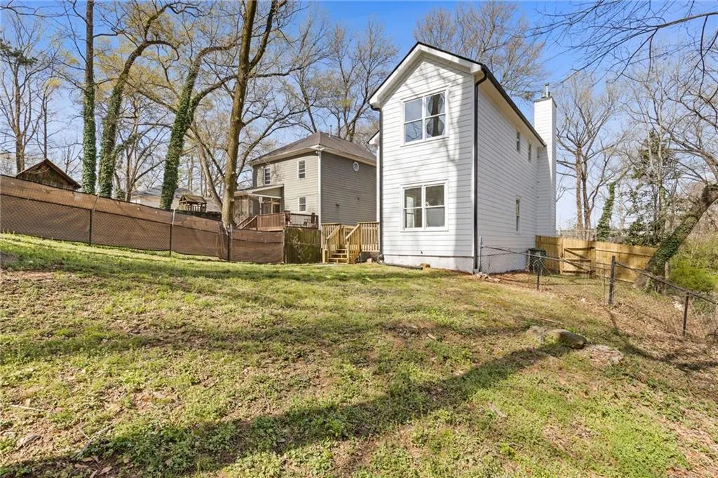 Back of property featuring a fenced backyard, a wooden deck, and a chimney