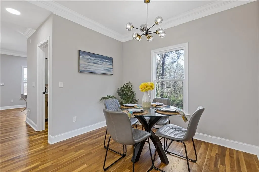 Dining area with ornamental molding, wood finished floors, and a chandelier