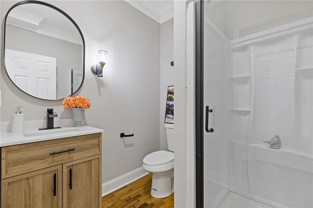 Bathroom featuring vanity, light wood-type flooring, a stall shower, and ornamental molding