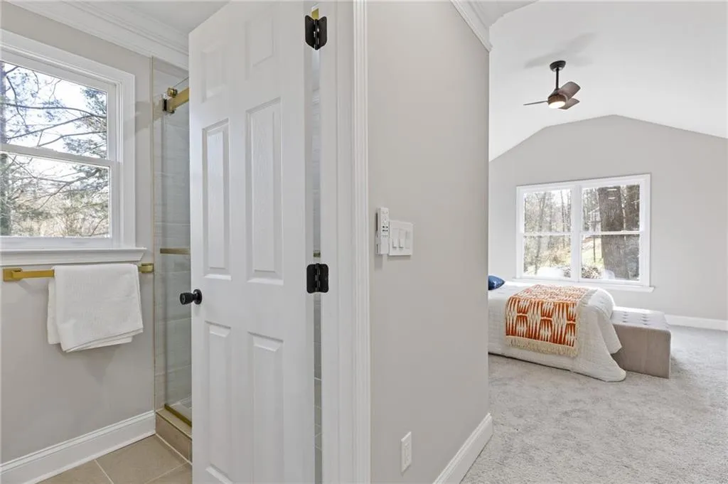 Full bath featuring a stall shower, vaulted ceiling, ceiling fan, and light tile patterned floors