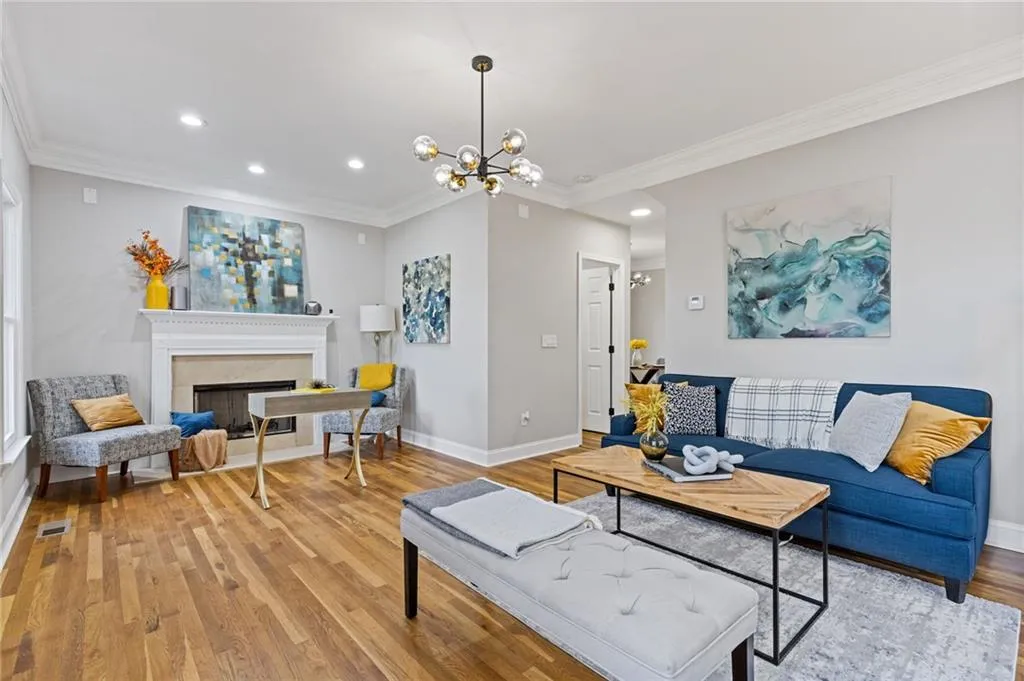 Living room with crown molding, recessed lighting, wood finished floors, a fireplace, and a chandelier