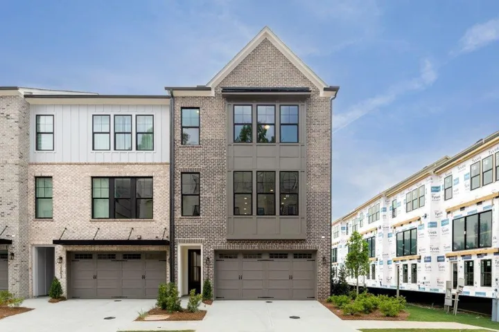 Contemporary townhome facade featuring a brick exterior with vertical siding accents