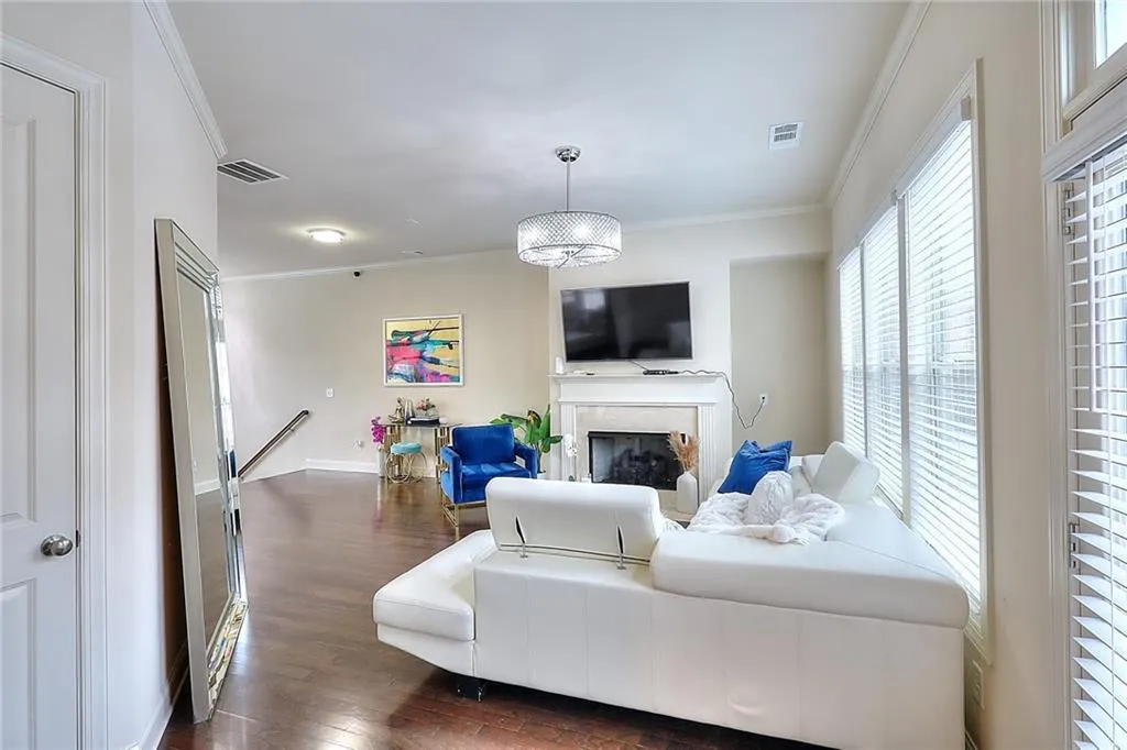 Living area with dark wood-type flooring, crown molding, and a fireplace