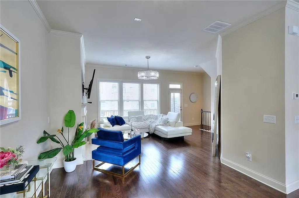Living area with a chandelier, dark wood-style floors, and crown molding