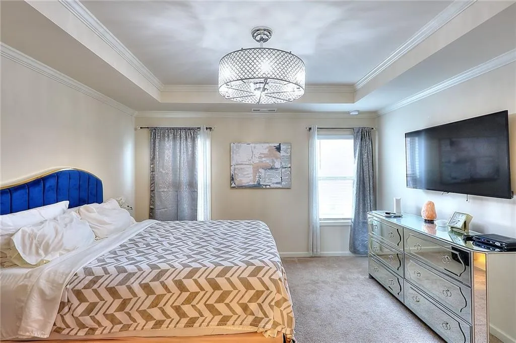 Bedroom with light colored carpet and a raised ceiling