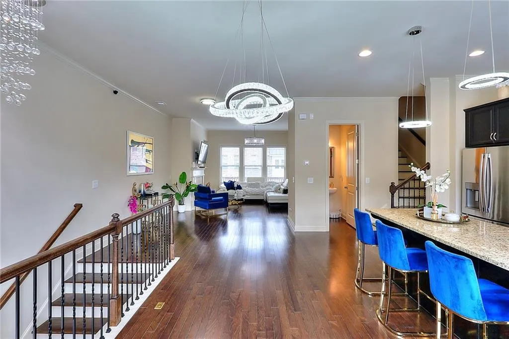 Upgraded Light Fixtures Kitchen with stainless steel fridge with ice dispenser, dark wood-style floors, light stone countertops, crown molding, and pendant lighting