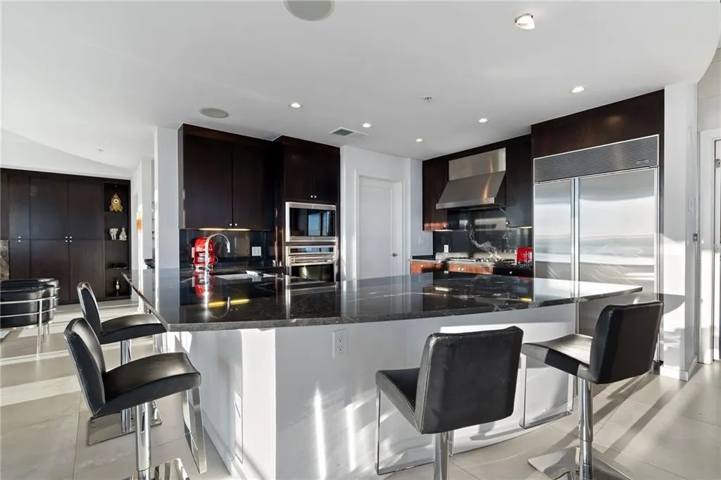 Kitchen featuring a breakfast bar, tasteful backsplash, built in appliances, light tile patterned floors, and recessed lighting Kitchen featuring a breakfast bar, tasteful backsplash, built in appliances, light tile patterned floors, and recessed lighting