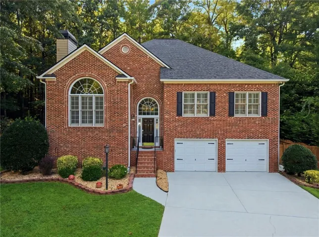 Brick exterior with arched windows, a two-car garage, and a concrete driveway