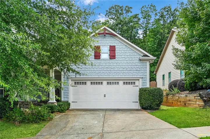 Front exterior featuring light blue scalloped siding, white trim, and a white garage door with decorative hardware