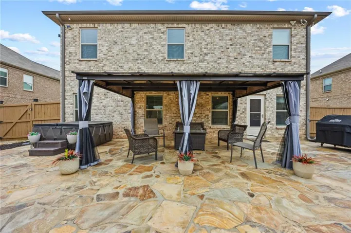 Expansive flagstone patio featuring a covered pergola structure with privacy curtains