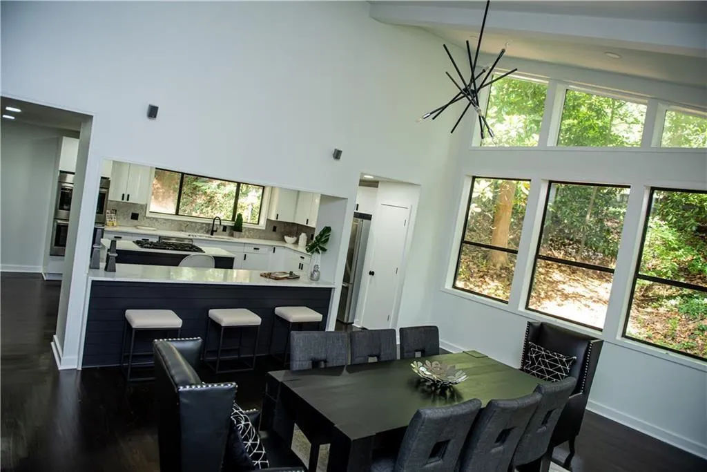 Dining area featuring dark wood-type flooring, a towering ceiling, and beam ceiling