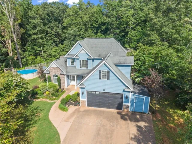Two-story residence featuring light blue siding, a dark gray garage door, and a stone facade accent