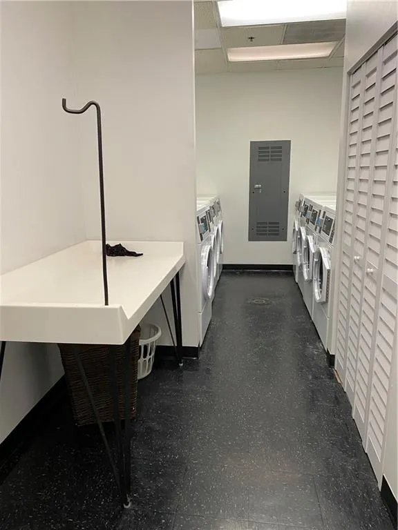 Community laundry room featuring baseboards, dark floors, and washer and dryer