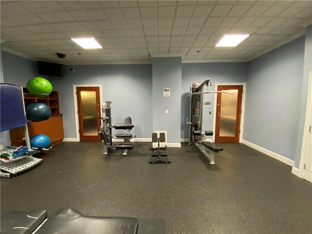 Gym featuring a paneled ceiling and baseboards