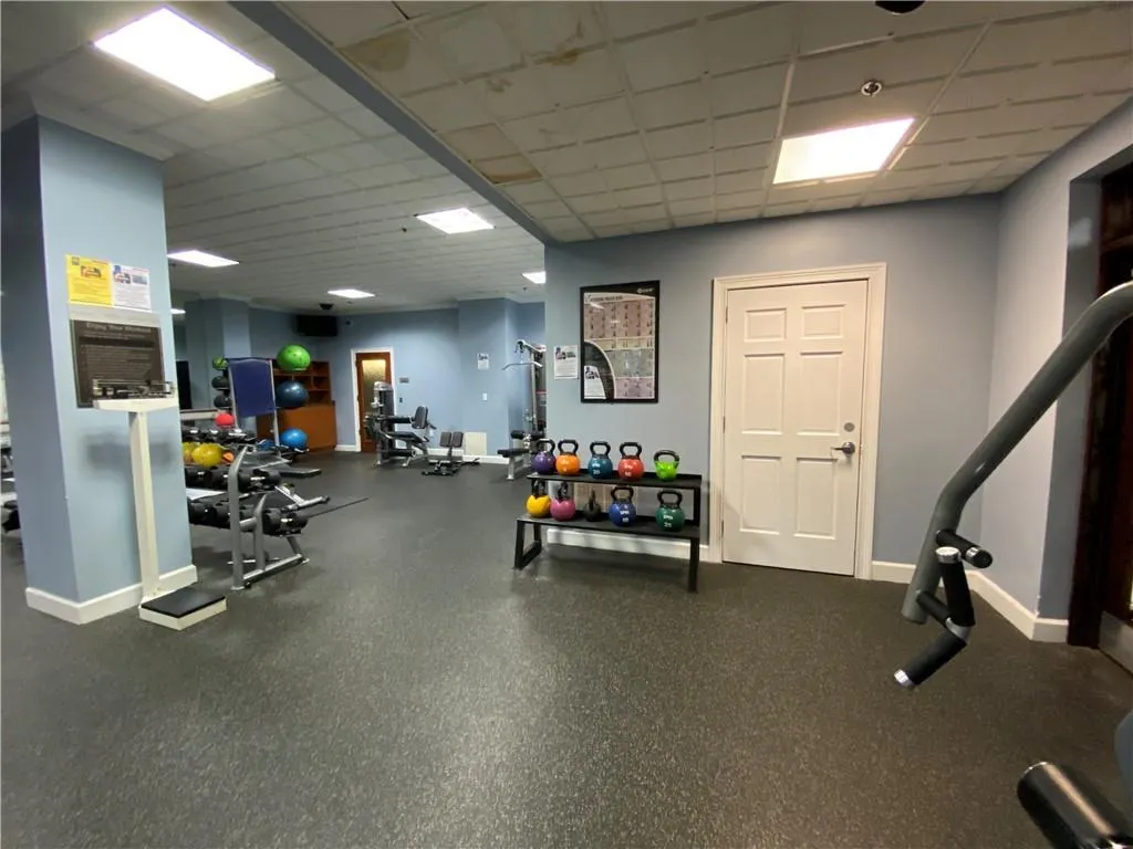 Exercise room with a paneled ceiling and baseboards