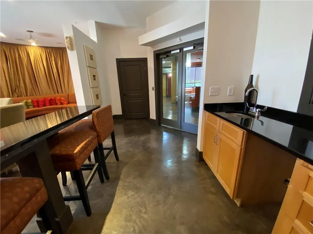 Kitchen featuring french doors, dark countertops, a sink, and finished concrete floors