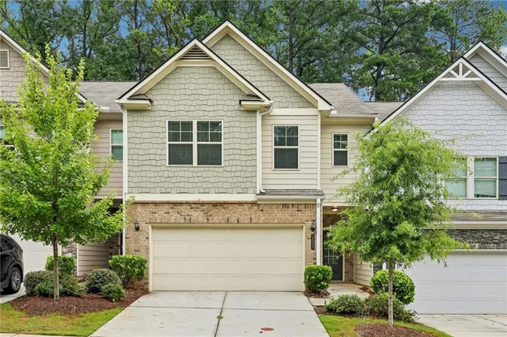 Charming two-story residence featuring a cream-colored brick and siding exterior with peaked gable roofline and dentil molding details