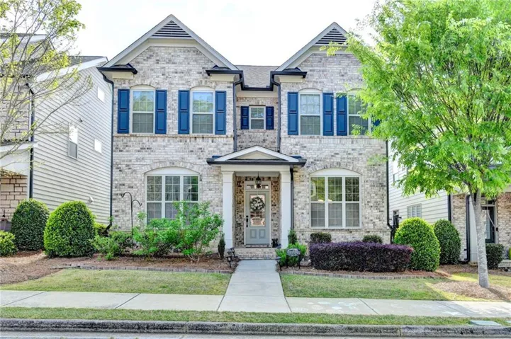 Two-story brick facade residence with a columned front porch and mature landscaping