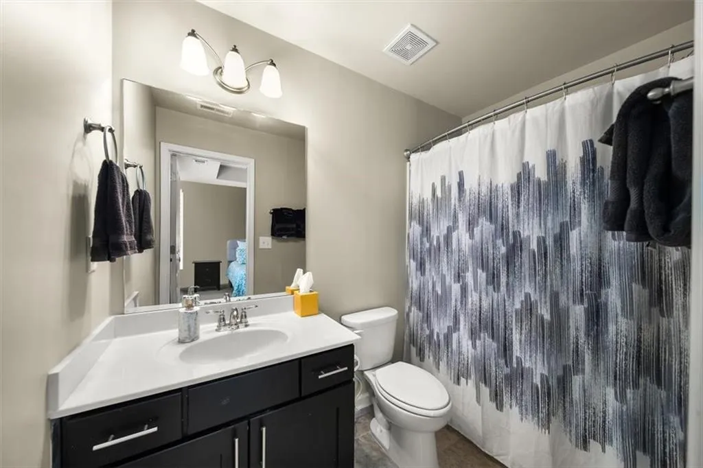 Bathroom featuring a shower with shower curtain, vanity, toilet, and tile patterned flooring