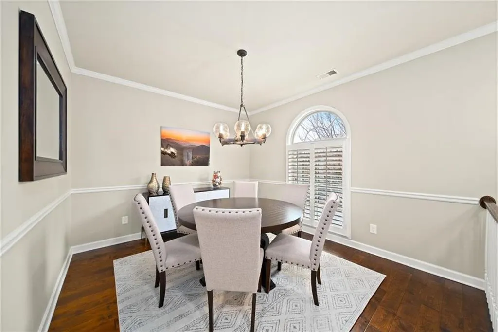 Dining room with ornamental molding, dark hardwood / wood-style floors, and an inviting chandelier