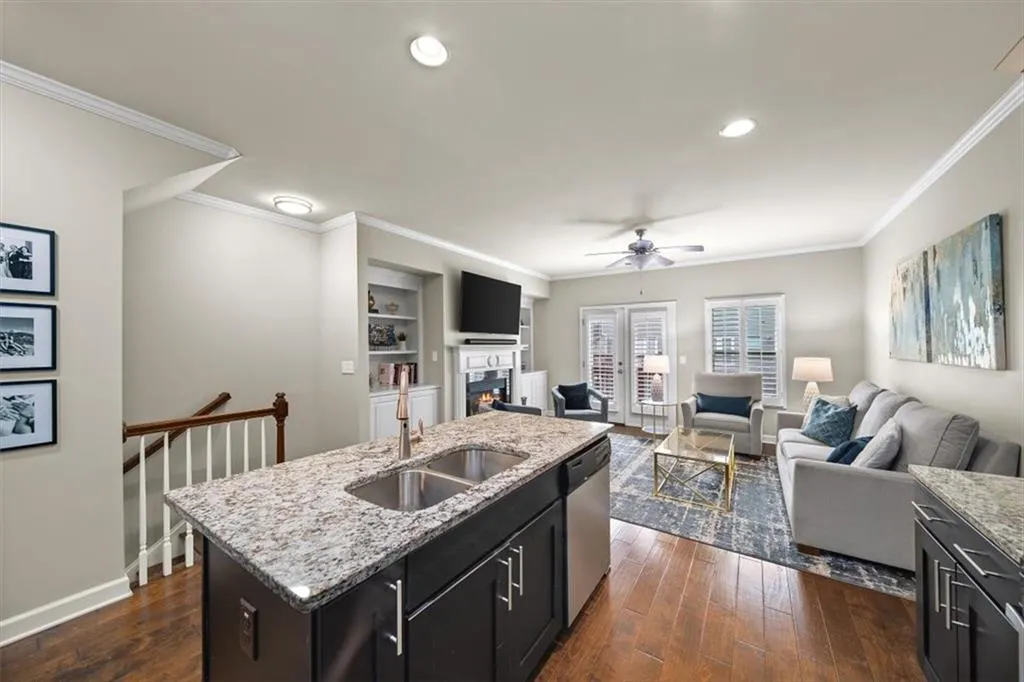Kitchen featuring dark wood-type flooring, stainless steel dishwasher, sink, and an island with sink