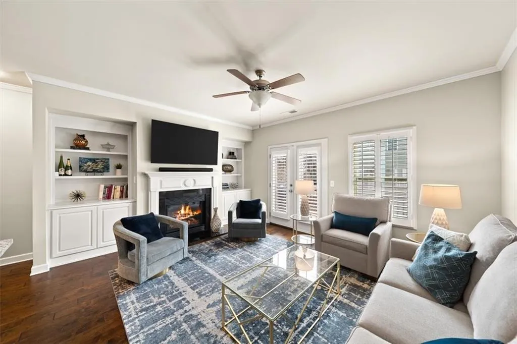 Living room featuring built in shelves, ceiling fan, ornamental molding, and dark hardwood / wood-style flooring