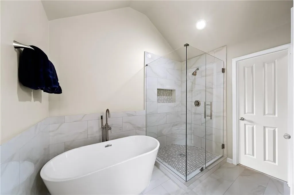 Bathroom featuring lofted ceiling, independent shower and bath, and tile walls