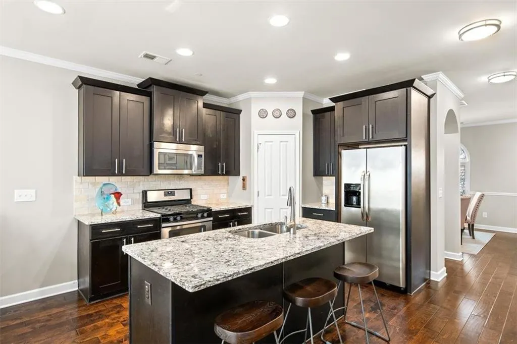 Kitchen featuring tasteful backsplash, sink, a breakfast bar area, stainless steel appliances, and a center island with sink