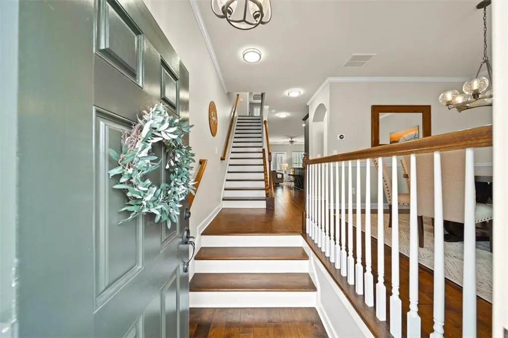 Stairway featuring ornamental molding, wood-type flooring, and a chandelier