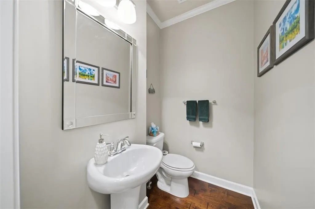 Bathroom featuring crown molding, wood-type flooring, sink, and toilet
