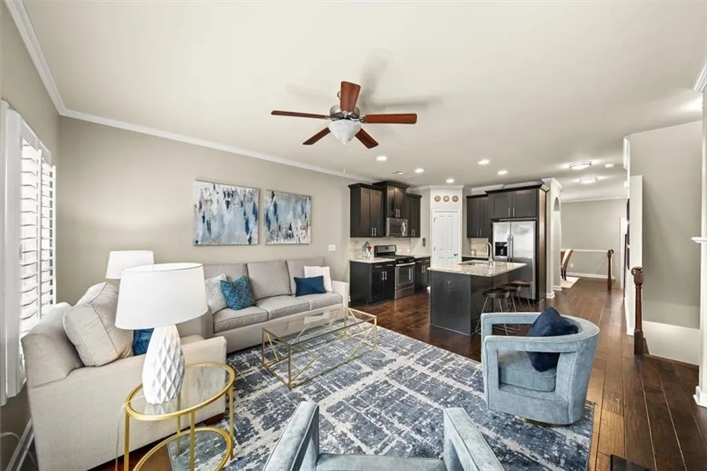 Living room featuring ceiling fan, ornamental molding, dark hardwood / wood-style floors, and sink