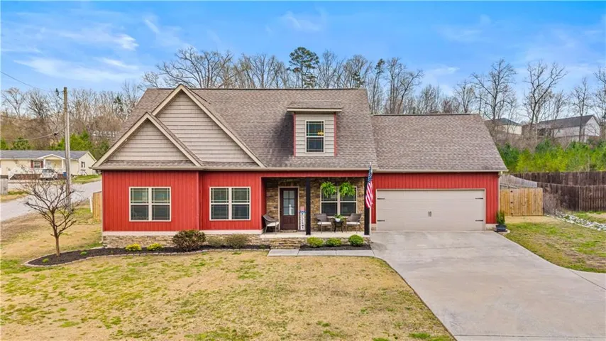 Craftsman house featuring covered porch, driveway, roof with shingles, and an attached garage