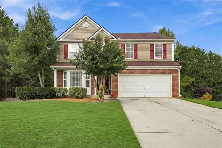 Two-story residence featuring brick and siding facade, bay window, two-car garage, and a concrete driveway