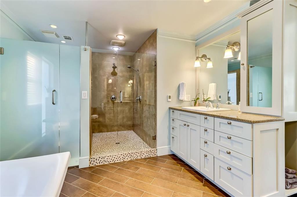 Oversized custom Shower with Dual Shower Heads & separate Water closet tastefully sited behind  the smoky green glass