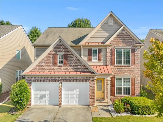 Brick and siding exterior with gabled roof lines, copper-toned metal awnings, and a two-car garage