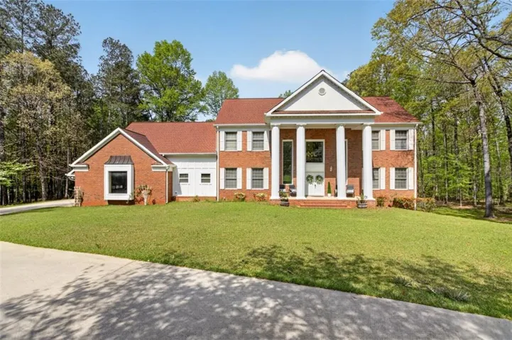 Neoclassical home featuring covered porch, a front lawn, and brick siding