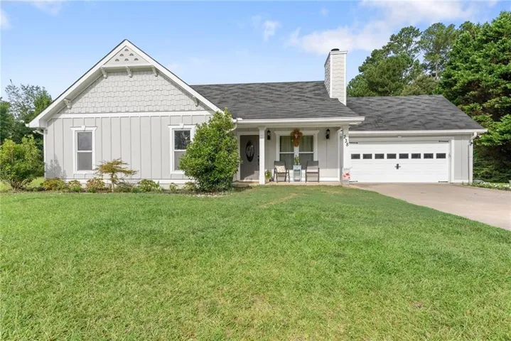 Exterior featuring light gray siding, dark shingle roof, gabled entry, attached two-car garage, and a concrete driveway