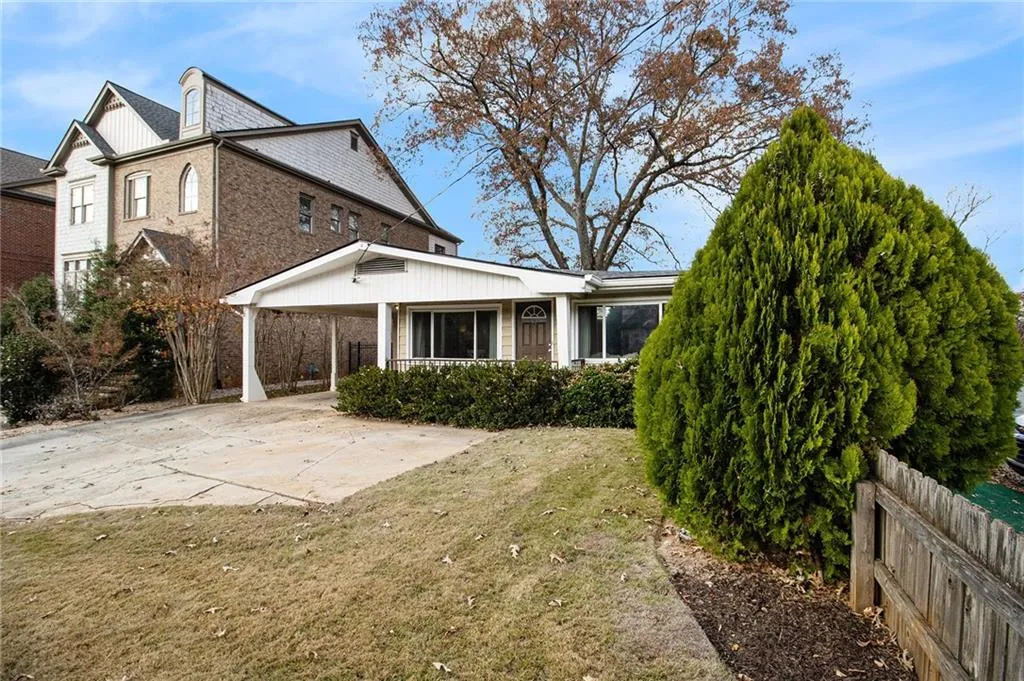 Back of property with driveway, covered porch, brick siding, and an attached carport