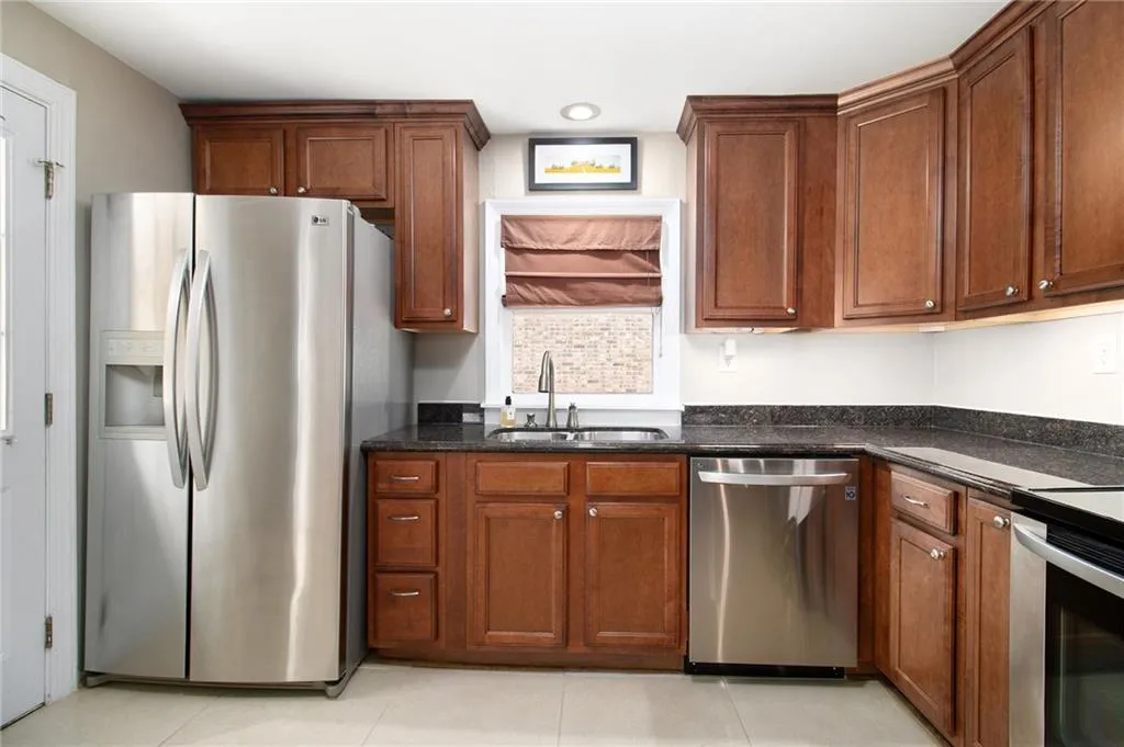 Kitchen with stainless steel appliances, dark stone counters, and brown cabinetry