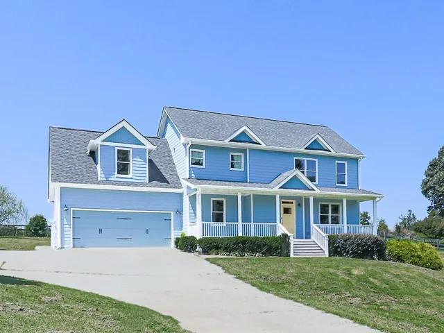 Two-story exterior with light blue siding, an attached two-car garage, and a covered front porch with white railings