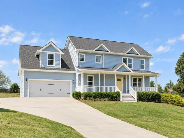 Two-story residence featuring light blue siding, a covered front porch, and a two-car garage with carriage-style doors