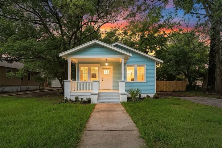 Cottage-style home with light blue siding, a covered front porch with white railings, and a concrete walkway