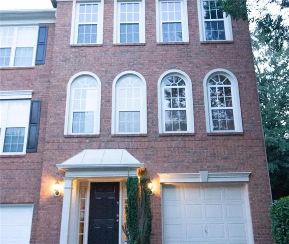 Colonial inspired home with brick siding and an attached garage