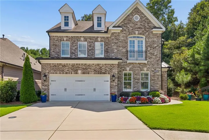 Brick exterior craftsman-style home featuring a two-car garage and decorative dormer windows