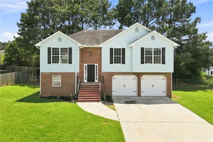Brick and vinyl Colonial-style residence featuring a two-story facade with multi-pane double-hung windows, a centered front entry with brick steps, and a covered front portico