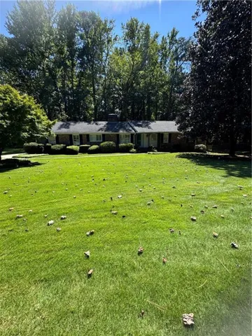 Brick exterior with white trim, a gabled roof, and mature trees providing natural screening